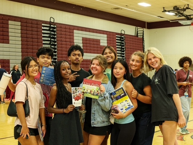 nine high school students standing with different college brochures for a group photo
