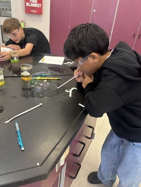 student blowing bubble with straw