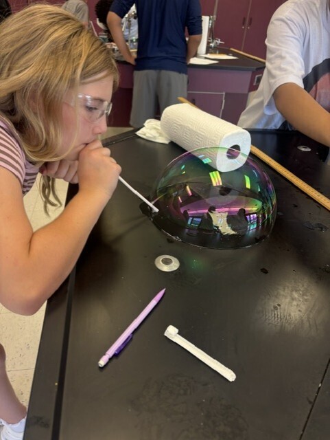 student blowing bubble with straw