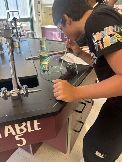 student blowing bubble with straw