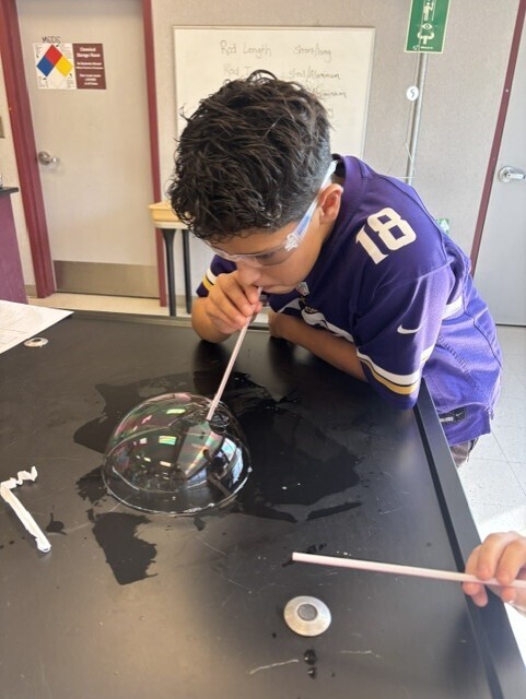 student blowing bubble with straw