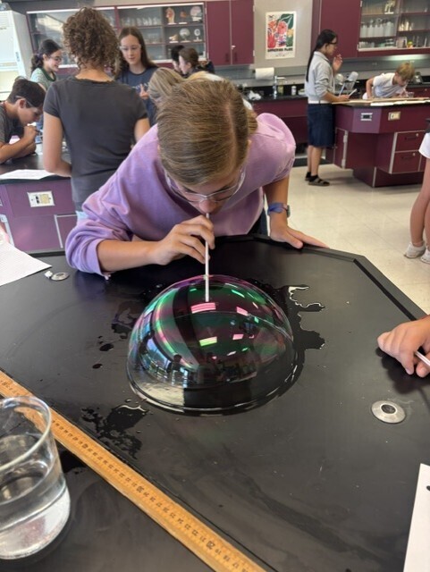student blowing bubble with straw