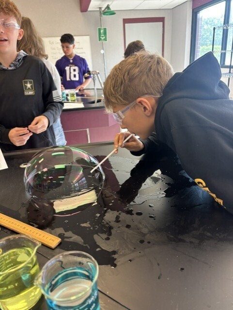 student blowing bubble with straw