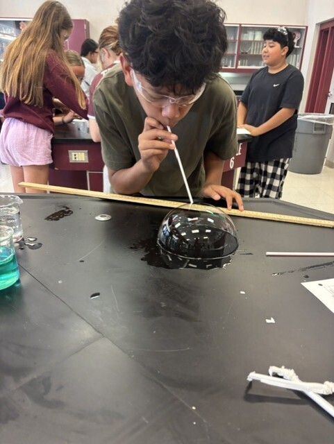 student blowing bubble with straw