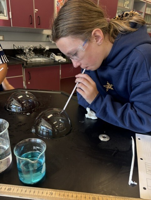 student blowing bubble with straw