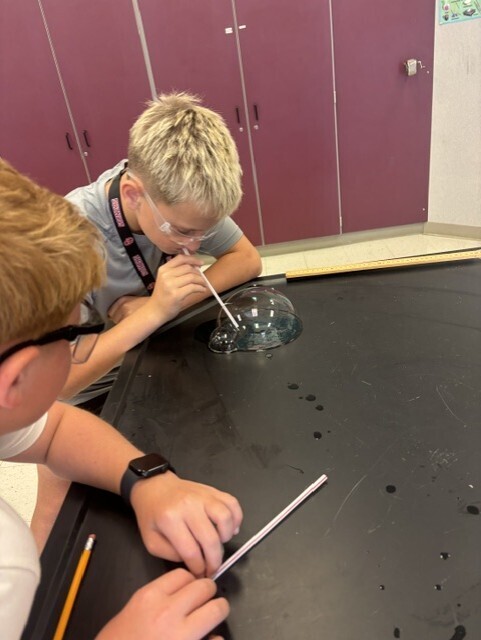 student blowing bubble with straw