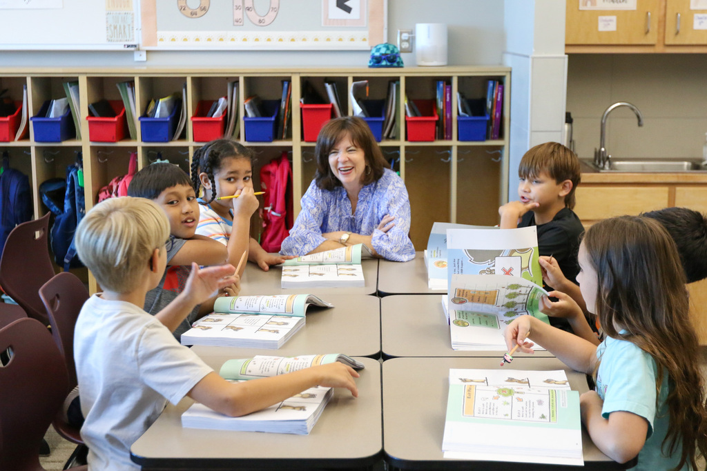 dr. butterfield sitting at the head of a table with 6 other 3rd graders. she is laughing
