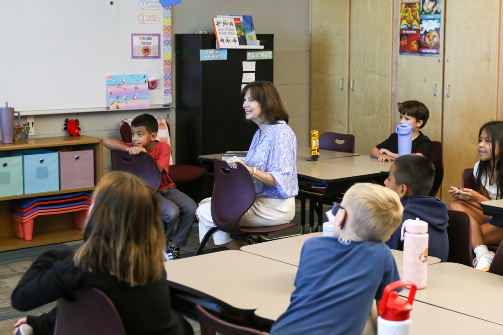 dr. Butterfield across the classroom smiling. students sit at their desk around her