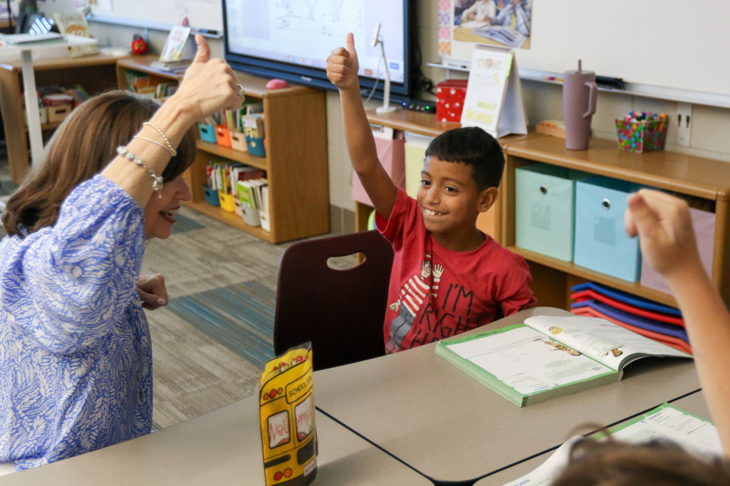 student has his thumbs up in the air showing he is done with a math problem. dr. butterfield is next to him doing the same. they are laughing