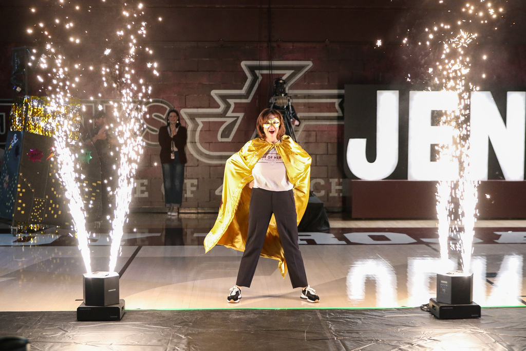 dr. butterfield in a gold caper in a hero power stance with sparks flying on either side of her