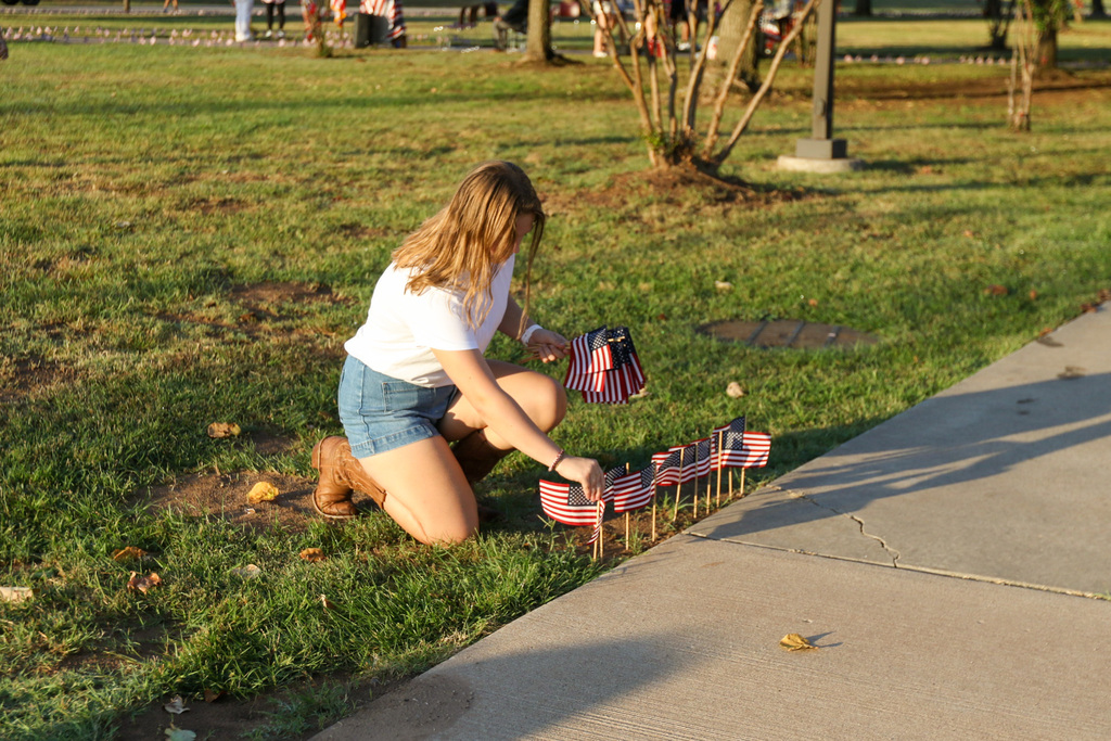 girl kneels down puting flags in the ground
