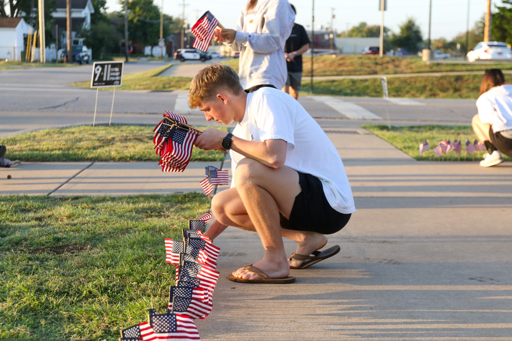 high school boy squatted down putting flags into the ground