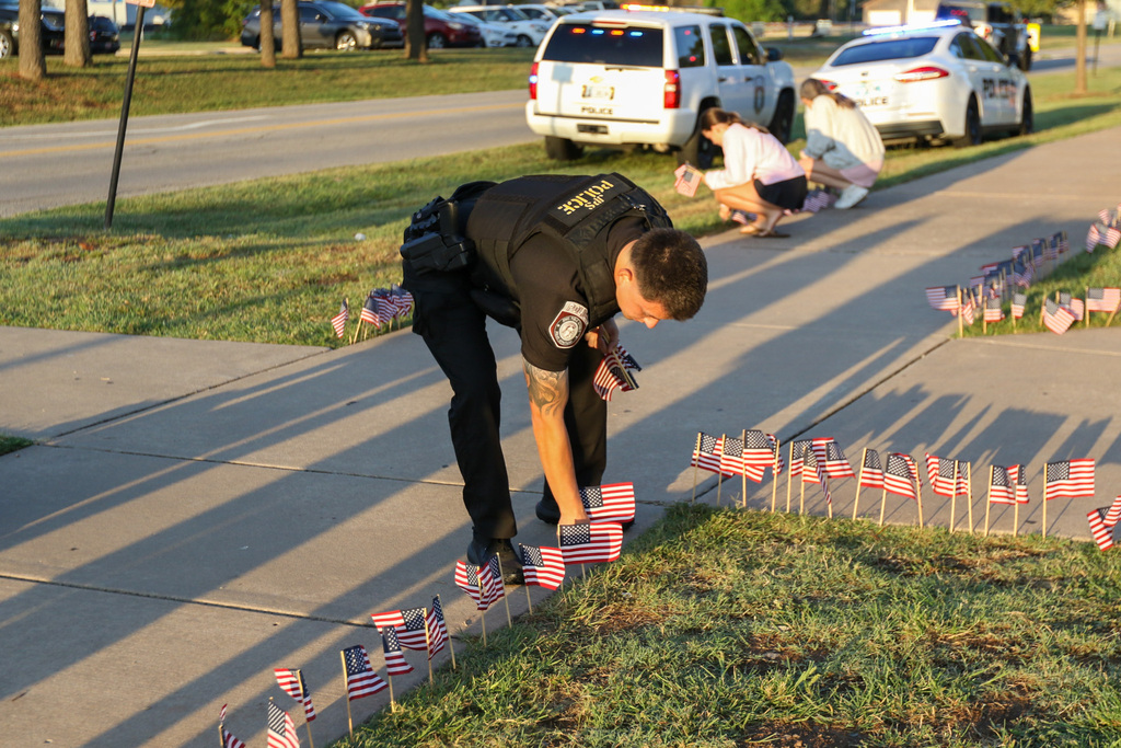jenks public schools police officer bent over putting flags in the ground