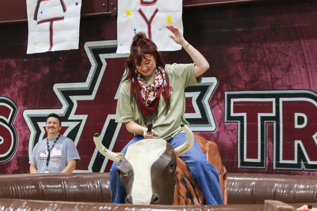 teacher on the inflatable bull with one arm up