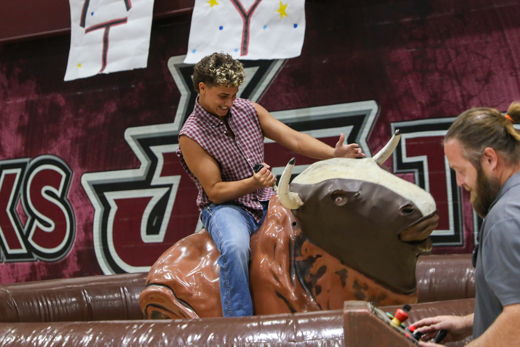 senior boy showing his strength as he hangs on to the inflatable bull