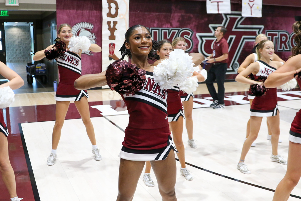 cheerleader smilig with her pompoms to her chest