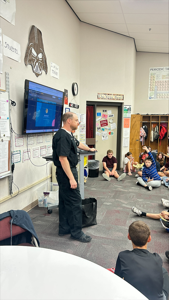 Doctor in scrubs presenting to a 6th grade science class to discuss the human body which connects to their learning in science class.
