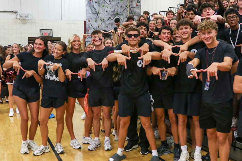 large group of seniors in all black outfits doing the upside down Union U with their hands