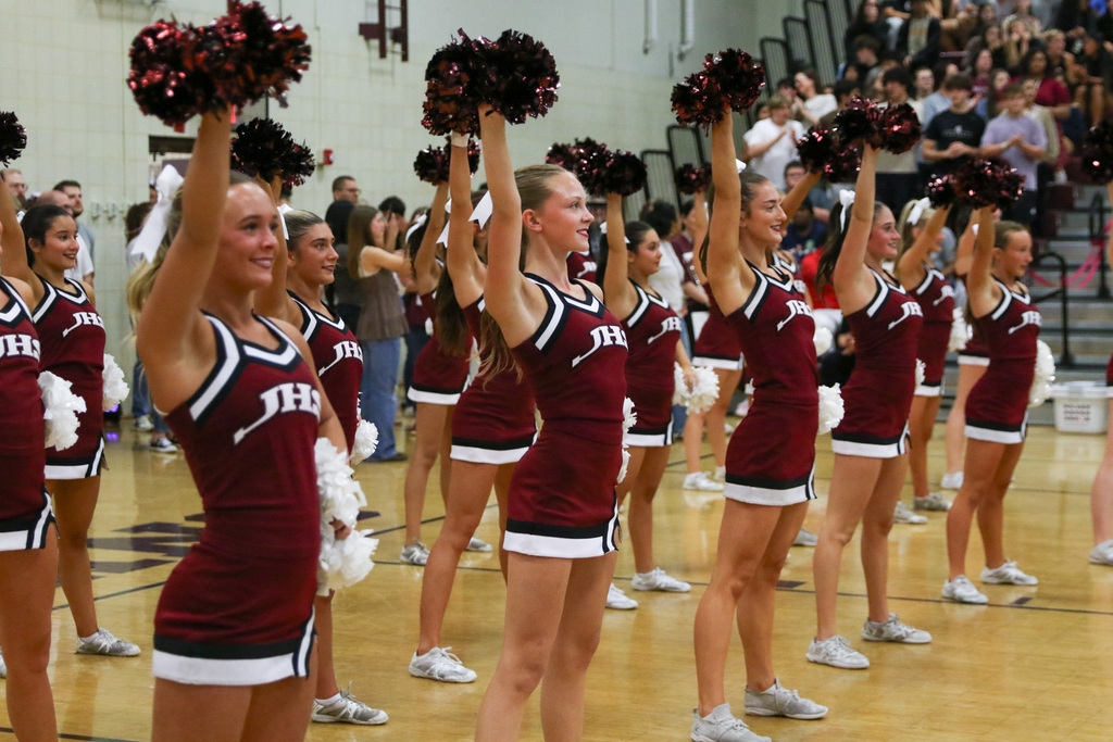 cheerleaders standing on the sideline with one arm up holding their pompom up