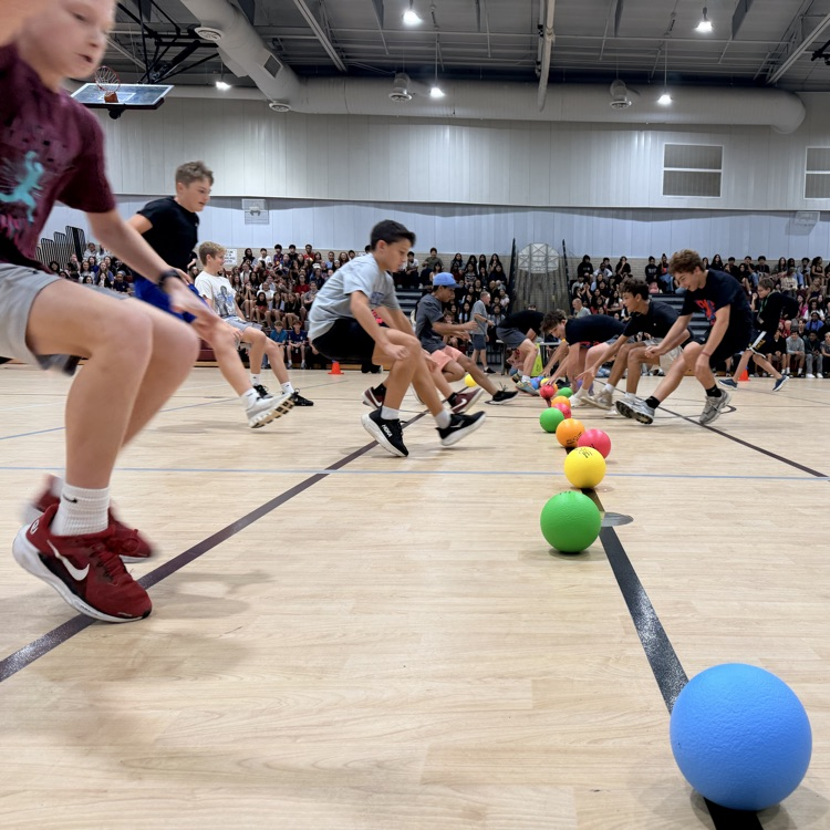 students running towards a center line to grab a dodgeball
