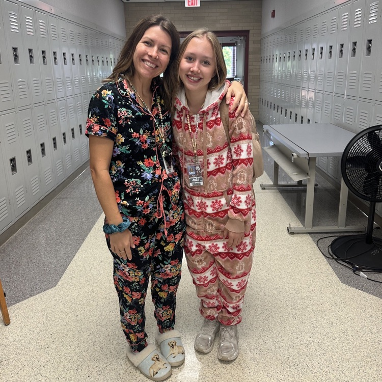 A teacher and student wearing pajamas in the hallway