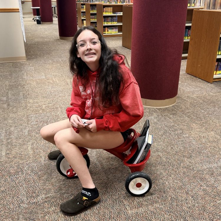 student riding a small trike has a backpack