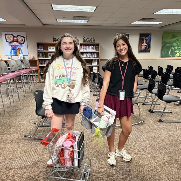 One student with a mini shopping cart the other with a shower caddy