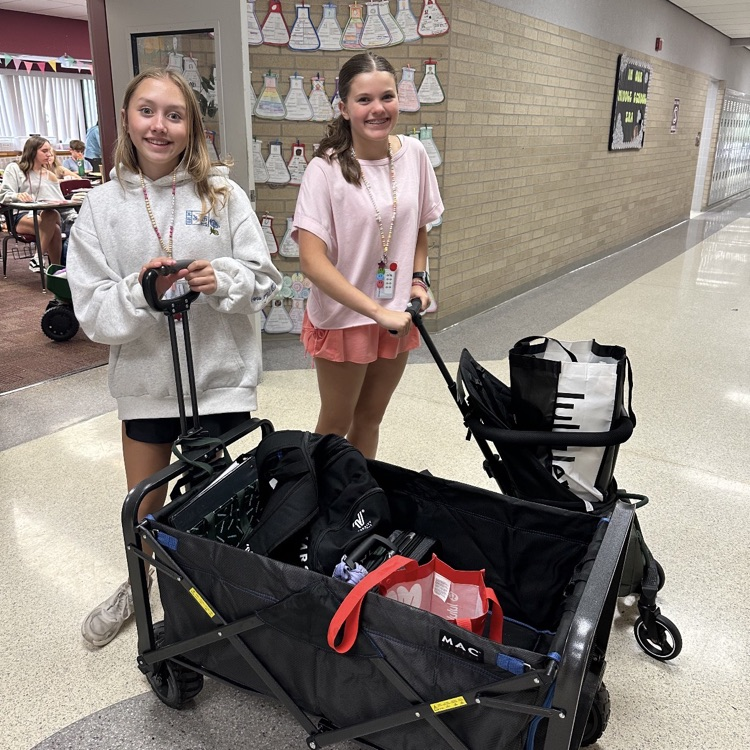 2 girls holding a wagon and stroller