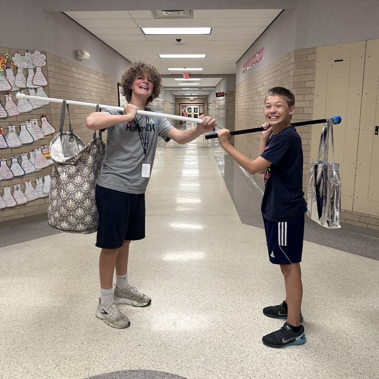 2 boys holding bags on poles
