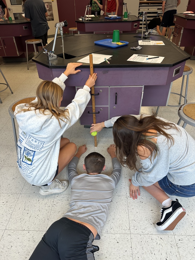 3 students measuring potential energy of their tennis ball