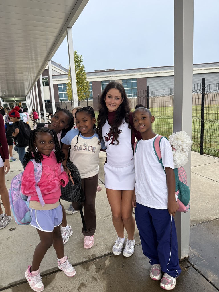 Cheerleader smiling with group of four students near Northwest Elementary