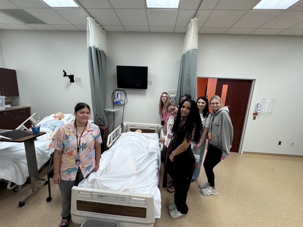 A group of students next to a hospital bed with a dummy in it 