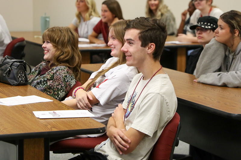 students sitting at desks smiling at speaker