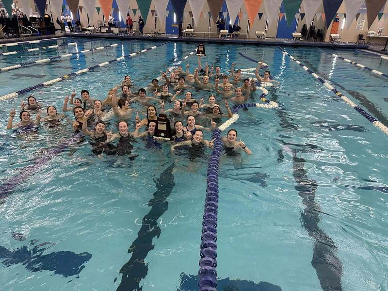 The swim team jumps into the pool with the trophy after winning 2026 state