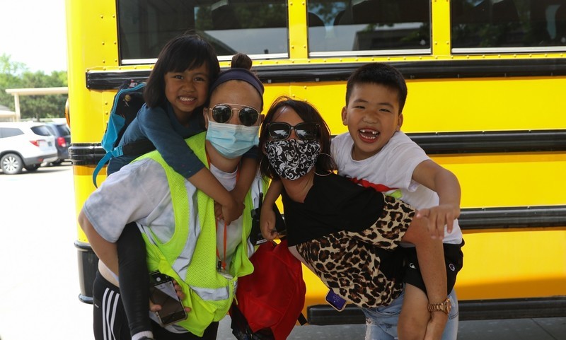 two adults holding two students piggyback