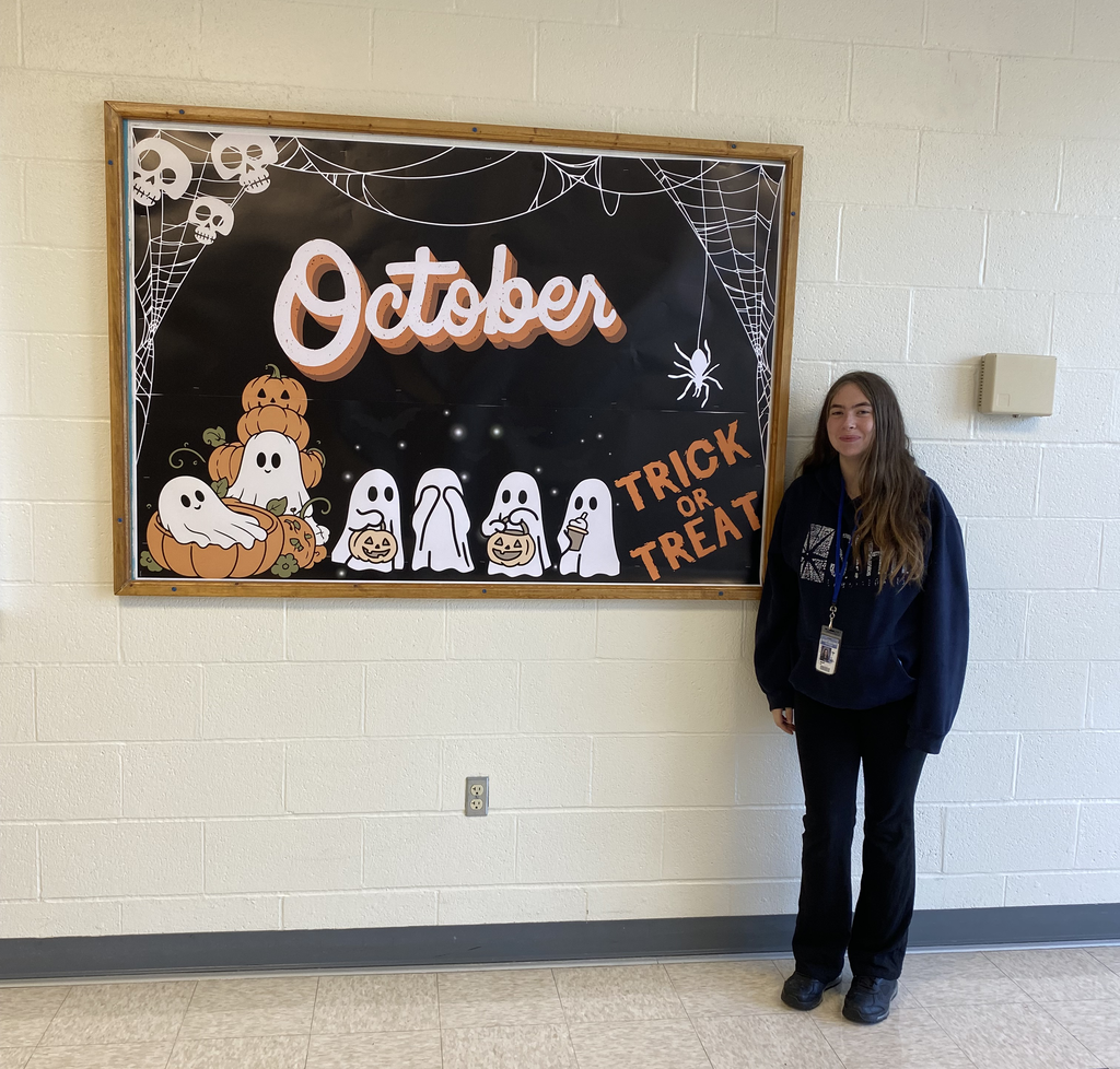 Student next to the bulletin board that reads "October"