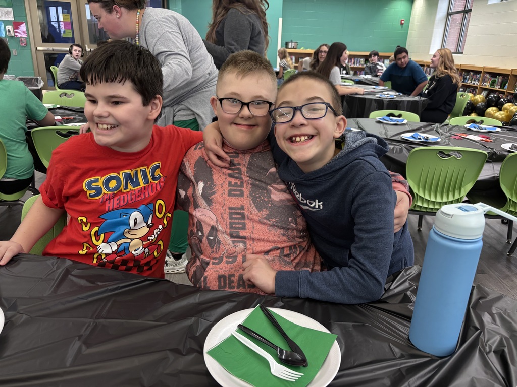 Three middle school students with their arms around each other, smiling.