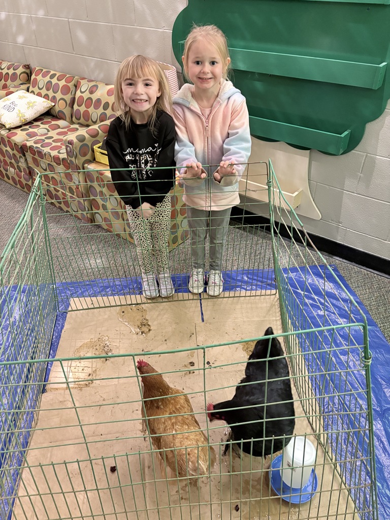 Two students stand with chickens