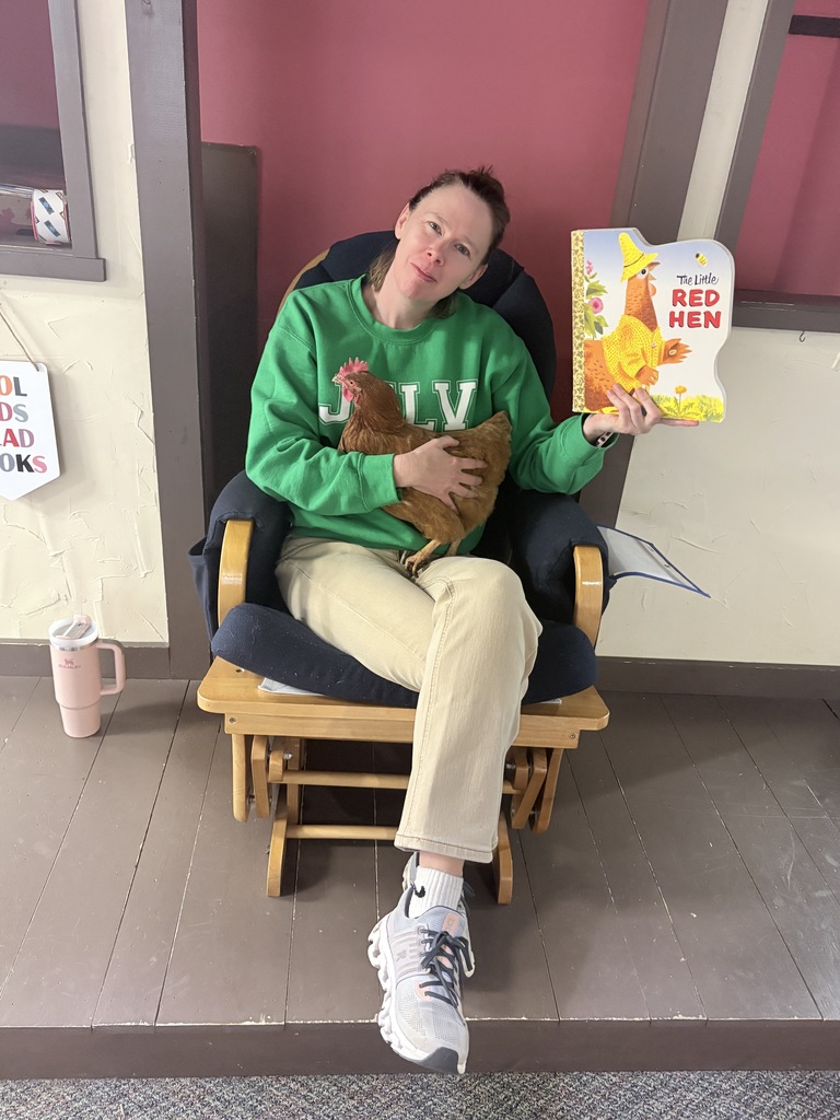 Mrs. Jessi holds the book red hen while holding a red hen