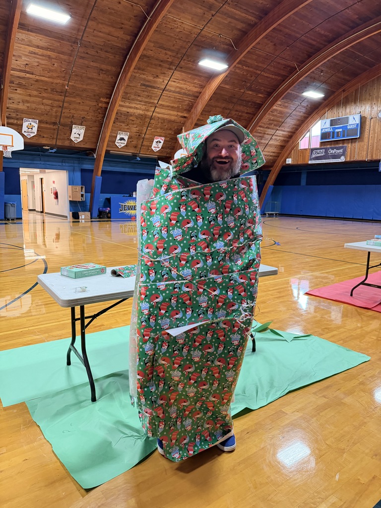Principal wrapped in green santa wrapping paper.