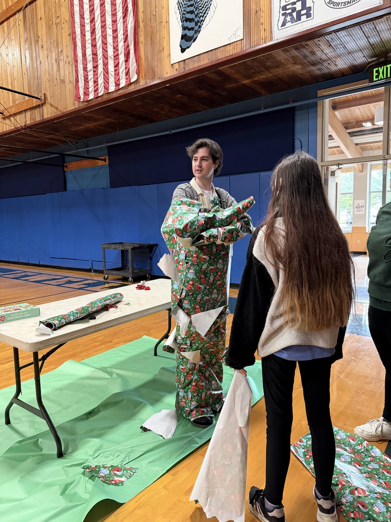 Teacher wrapped in green santa wrapping paper