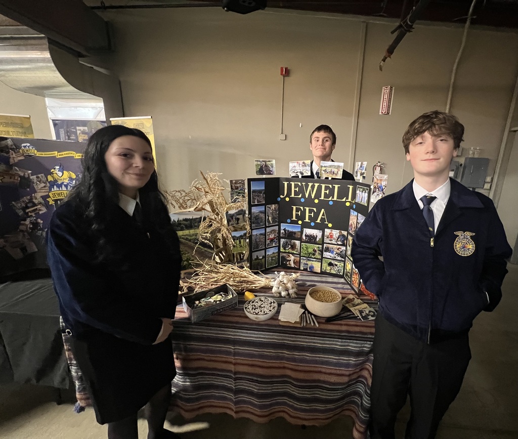 Students standing in front of a display board with photos of agriculture events.