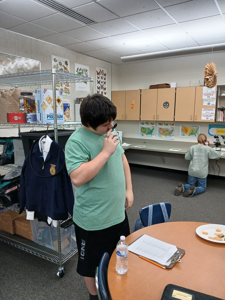 Students participating in a class activity by smelling a bottle to determine what is in it.