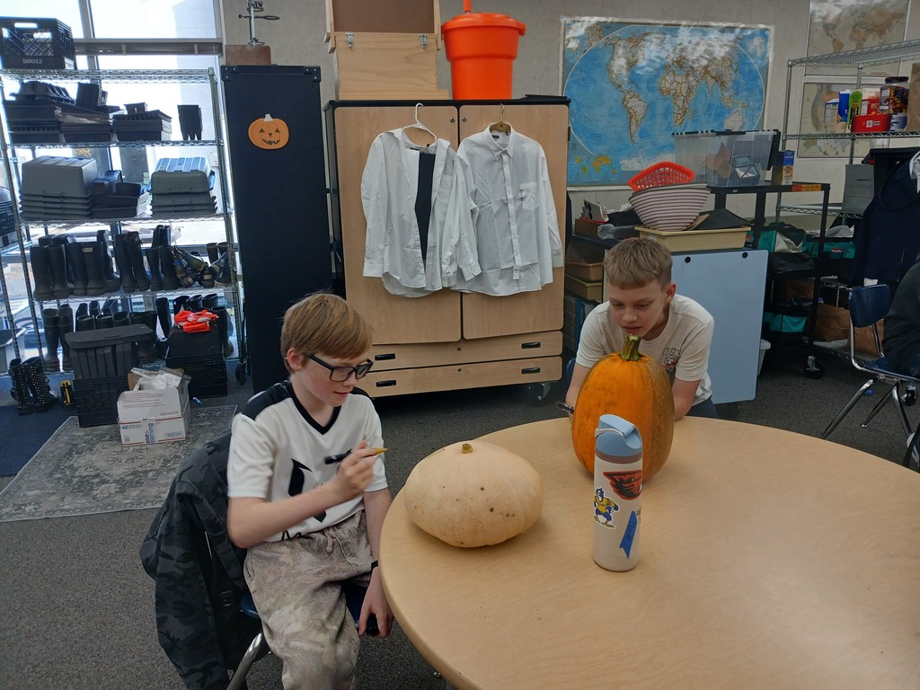 Students using paint pens to decorate their Halloween pumpkins.