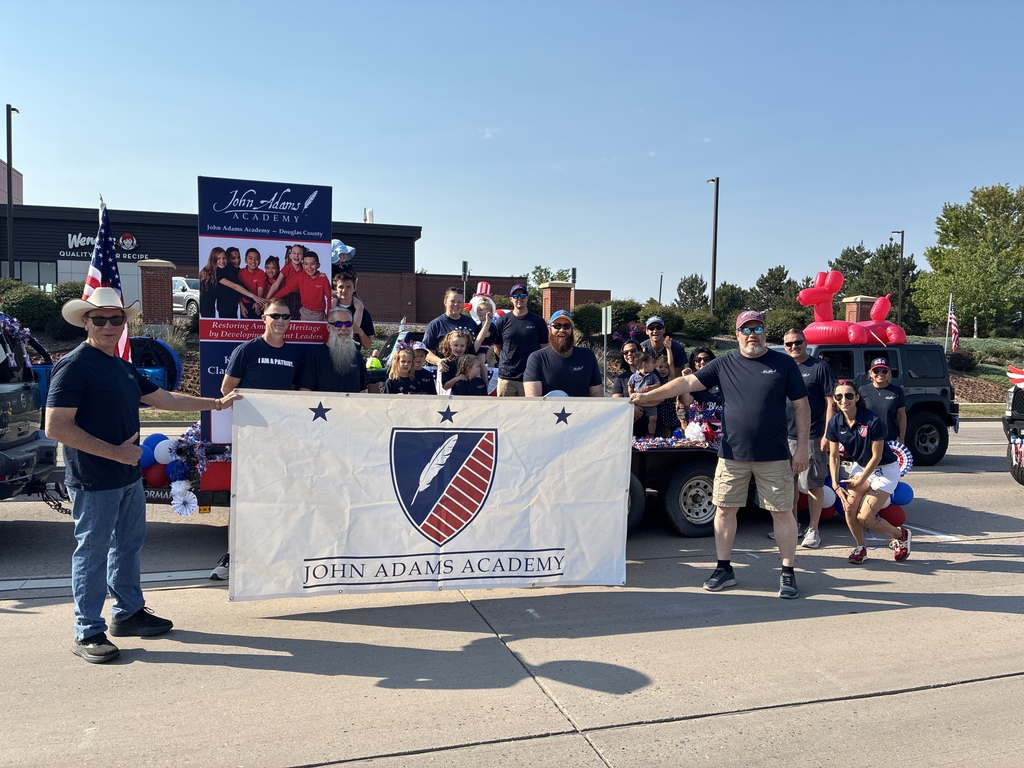 JAA families and faculty holding a banner for the 4th of July Parade.