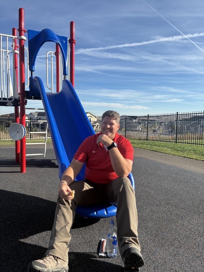 Photo of Mr. O'Shea sitting at the end of a slide