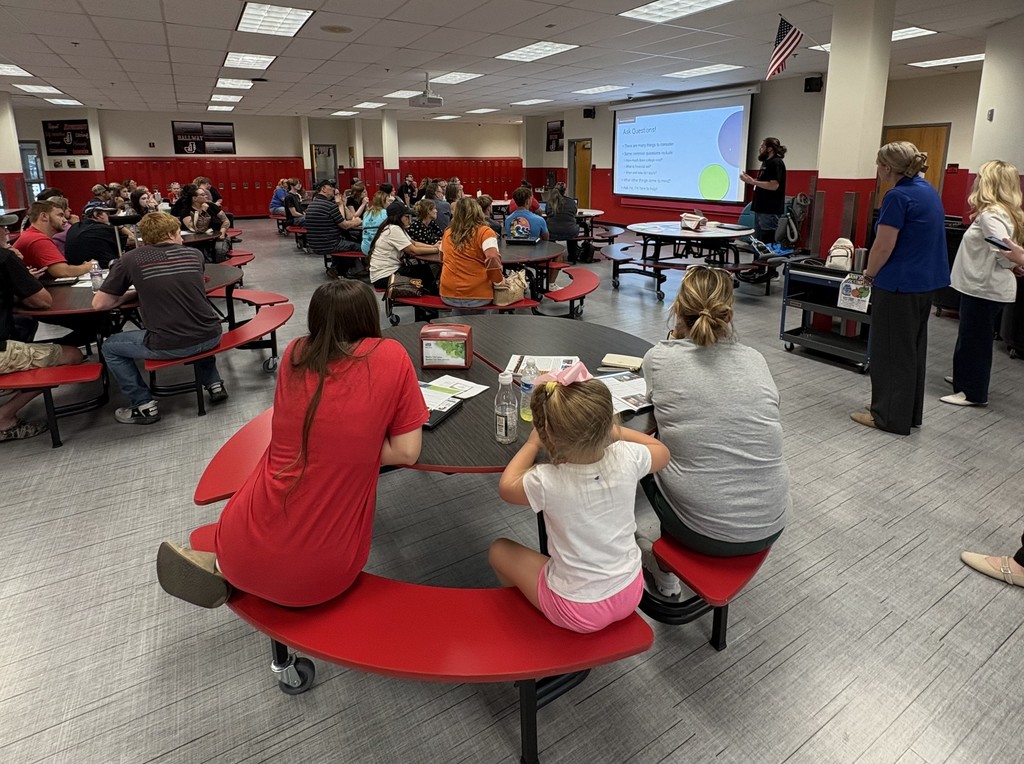 Parents and students sit in cafeteria listening to presentation for JCHS FAFSA Completion Night. 