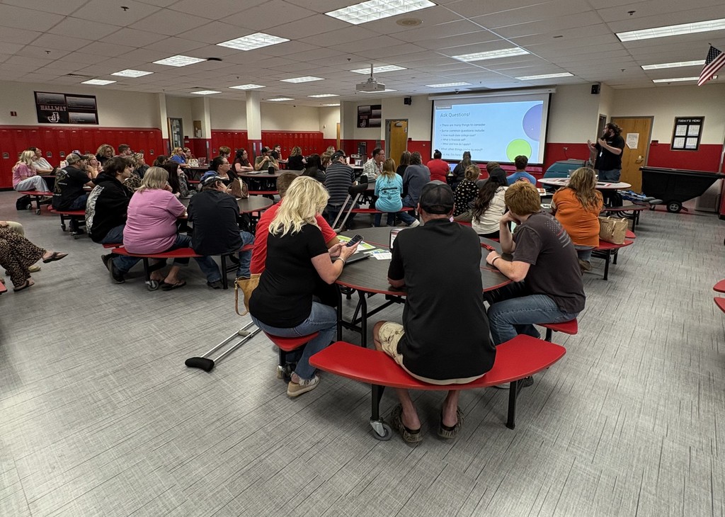 Parents and students sit in cafeteria listening to presentation for JCHS FAFSA Completion Night. 