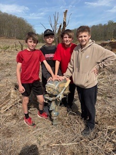 students pose with an old boat motor, found in the old lake bed