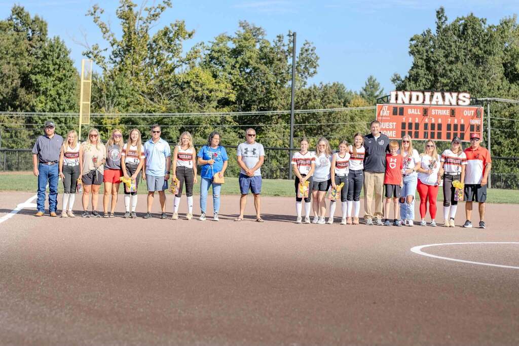 8th grade softball players stand with their parents on 8th grade night on 9/14/26